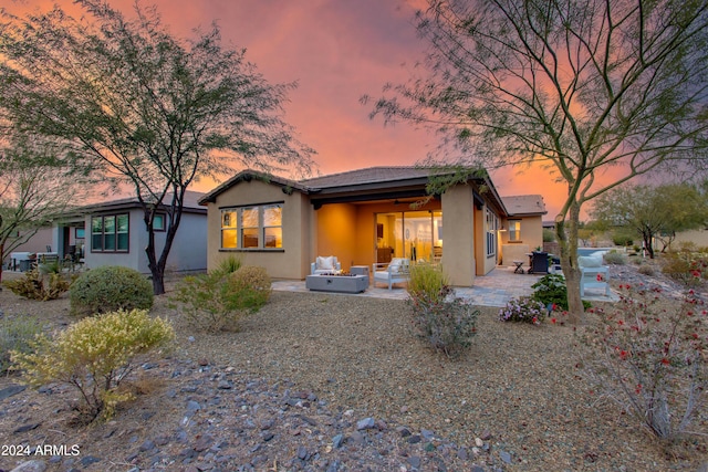 back house at dusk featuring outdoor lounge area and a patio area