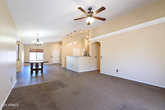 unfurnished living room with dark colored carpet, ceiling fan with notable chandelier, and high vaulted ceiling