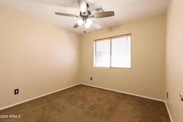 spare room featuring ceiling fan and dark carpet