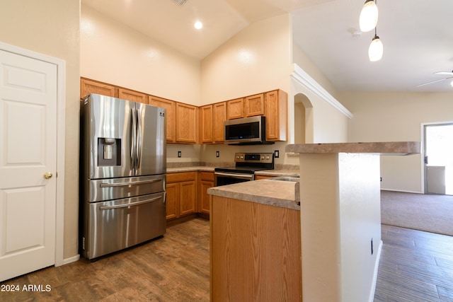 kitchen featuring dark hardwood / wood-style flooring, high vaulted ceiling, kitchen peninsula, pendant lighting, and appliances with stainless steel finishes