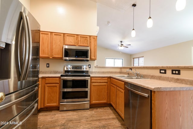 kitchen with ceiling fan, sink, stainless steel appliances, lofted ceiling, and decorative light fixtures