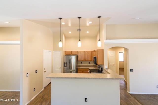 kitchen with kitchen peninsula, stainless steel refrigerator with ice dispenser, dark wood-type flooring, pendant lighting, and a high ceiling