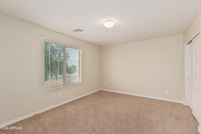 unfurnished bedroom featuring a closet and light colored carpet