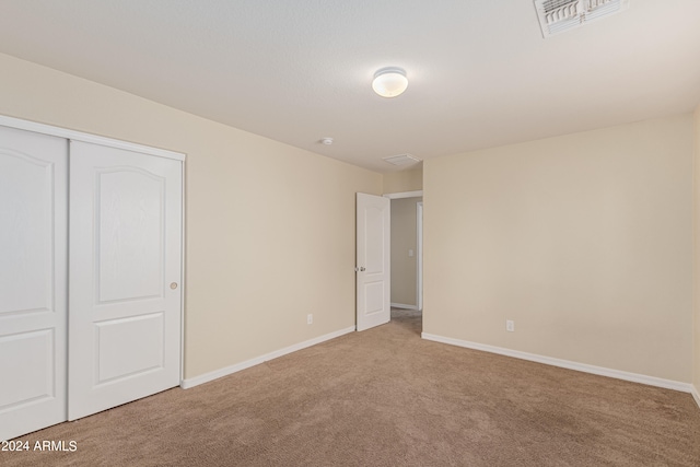 unfurnished bedroom featuring light carpet and a closet