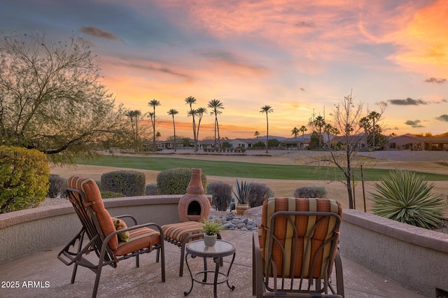 patio terrace at dusk featuring a lawn