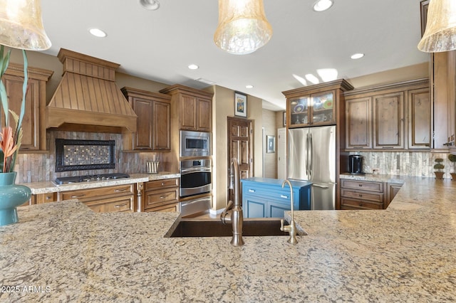 kitchen featuring sink, hanging light fixtures, appliances with stainless steel finishes, custom range hood, and backsplash