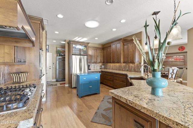 kitchen with sink, stainless steel appliances, a center island, light hardwood / wood-style floors, and custom exhaust hood