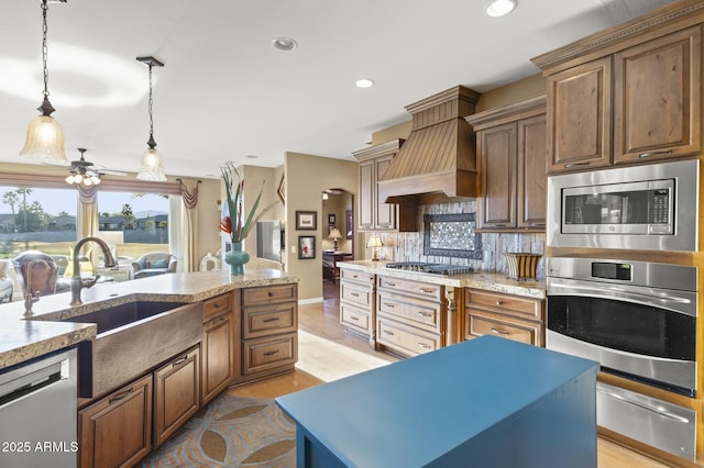 kitchen with premium range hood, decorative light fixtures, light wood-type flooring, stainless steel appliances, and decorative backsplash