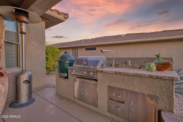 patio terrace at dusk with area for grilling and a grill