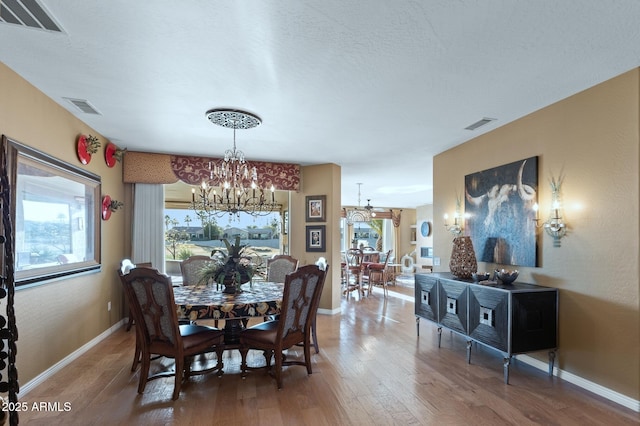 dining room featuring hardwood / wood-style floors, a textured ceiling, and a chandelier