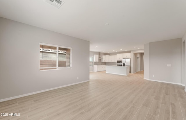 unfurnished living room featuring light wood-type flooring, baseboards, visible vents, and recessed lighting
