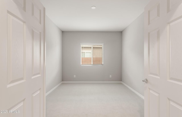 empty room featuring light carpet and baseboards