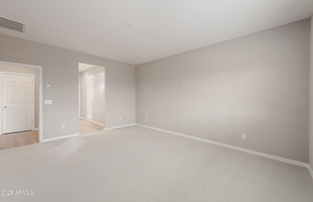 empty room with baseboards, light carpet, and visible vents