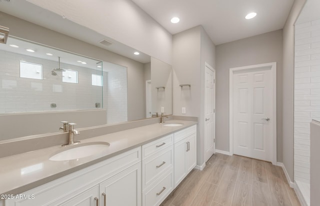 full bath with wood finished floors, a sink, a walk in shower, and double vanity