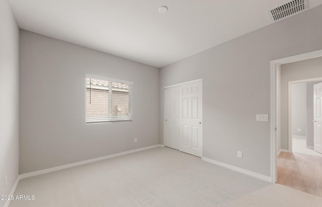 unfurnished bedroom featuring light colored carpet, baseboards, and visible vents