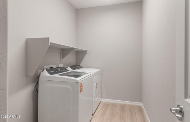laundry area with baseboards, light wood-type flooring, washer and dryer, and laundry area