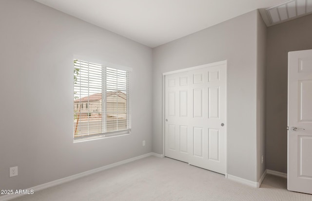 unfurnished bedroom featuring light colored carpet, baseboards, visible vents, and a closet