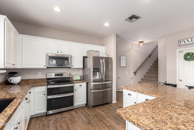 kitchen featuring white cabinetry, appliances with stainless steel finishes, dark wood-type flooring, and stone countertops