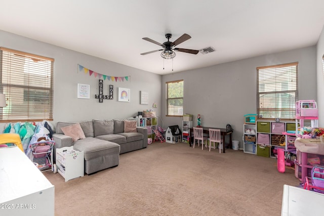 living room featuring ceiling fan, plenty of natural light, and light carpet