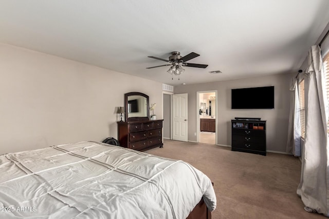 bedroom featuring light colored carpet, ceiling fan, and ensuite bath