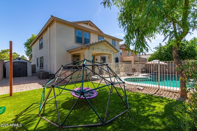 back of property with a fenced in pool, a lawn, central air condition unit, and a storage unit