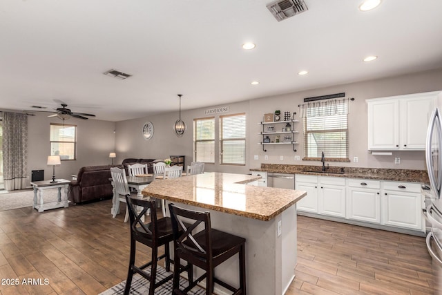 kitchen with light stone countertops, sink, hanging light fixtures, and white cabinets