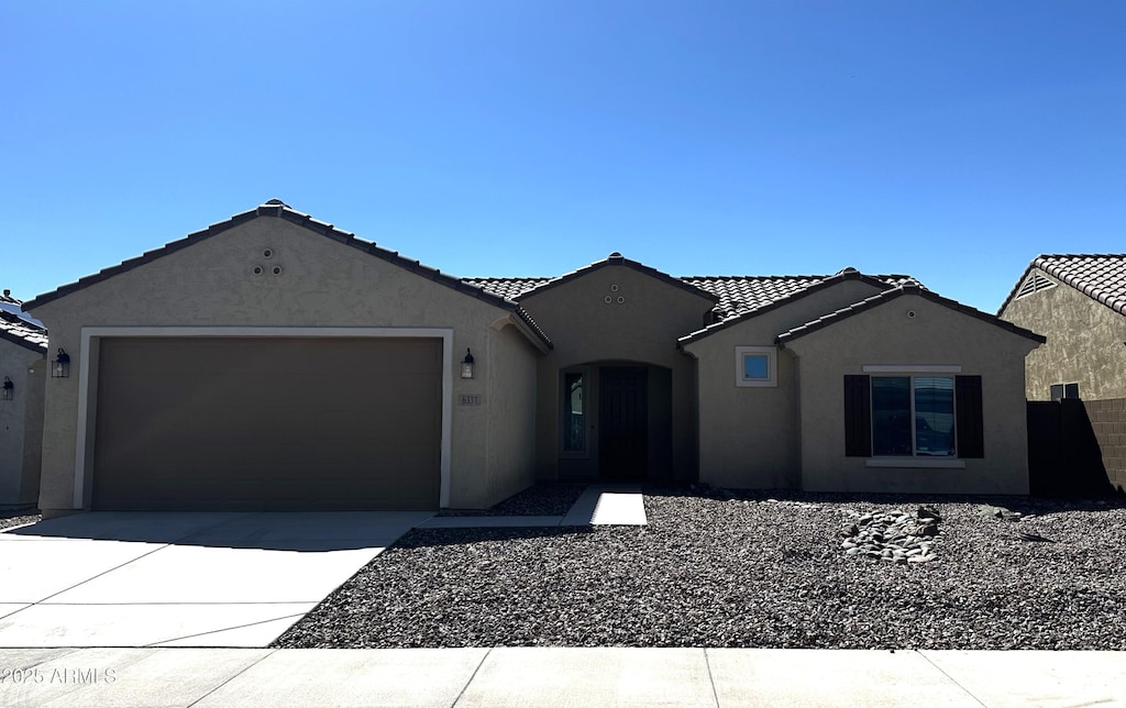 ranch-style house featuring a garage, concrete driveway, a tiled roof, and stucco siding