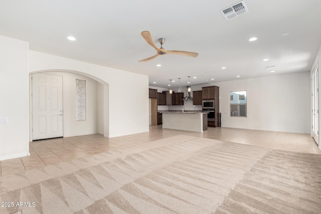 6331 W Desert Blossom Way, Florence, AZ 85132 - unfurnished living room featuring light tile patterned floors, arched walkways, ceiling fan, and recessed lighting