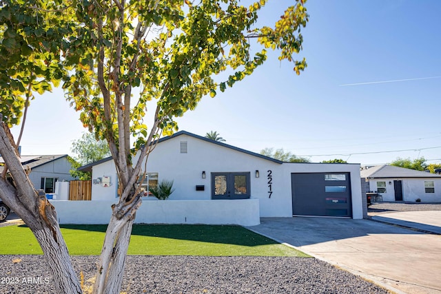 view of front of house featuring driveway, a garage, stucco siding, fence, and a front yard