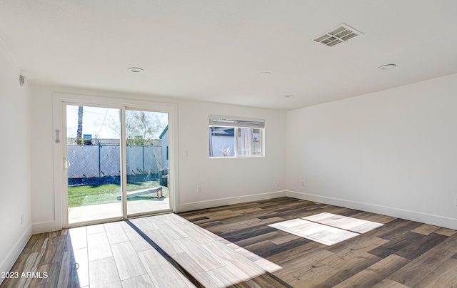 spare room featuring visible vents, baseboards, and wood finished floors