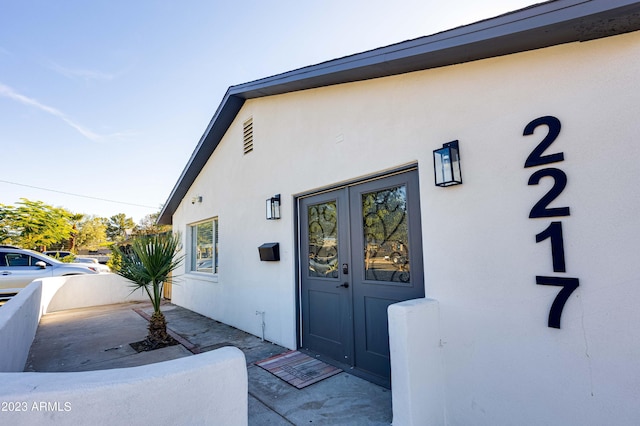 doorway to property featuring fence and stucco siding