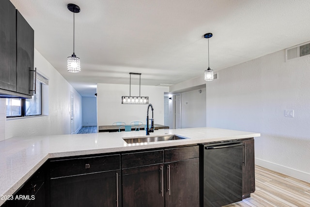 kitchen featuring light wood-style flooring, a sink, visible vents, dishwasher, and pendant lighting