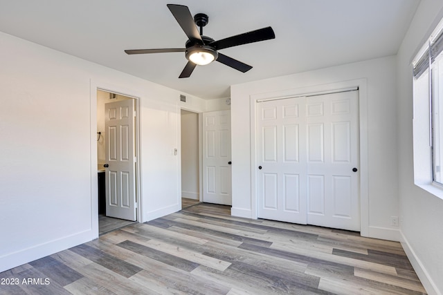 unfurnished bedroom featuring a closet, multiple windows, baseboards, and wood finished floors