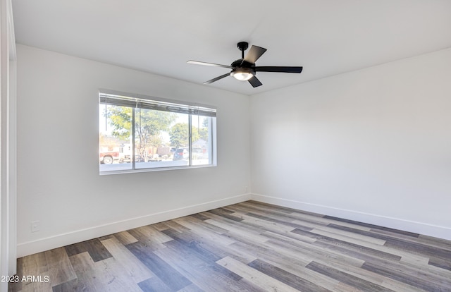 spare room featuring ceiling fan, baseboards, and wood finished floors