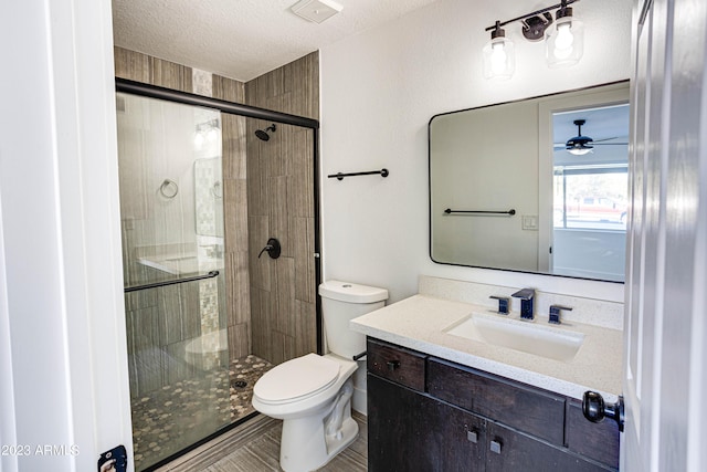 bathroom featuring vanity, a shower stall, toilet, and a textured ceiling