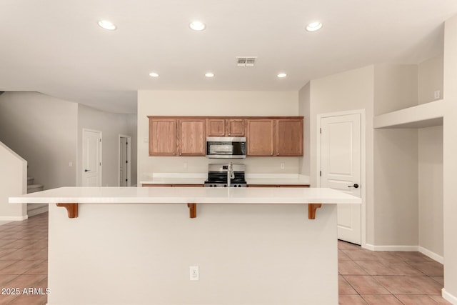17419 W Elaine Dr, Goodyear, AZ 85338 - kitchen with appliances with stainless steel finishes, light tile patterned floors, light countertops, recessed lighting, and a kitchen bar