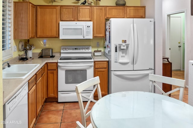 kitchen with light tile patterned flooring, white appliances, and sink