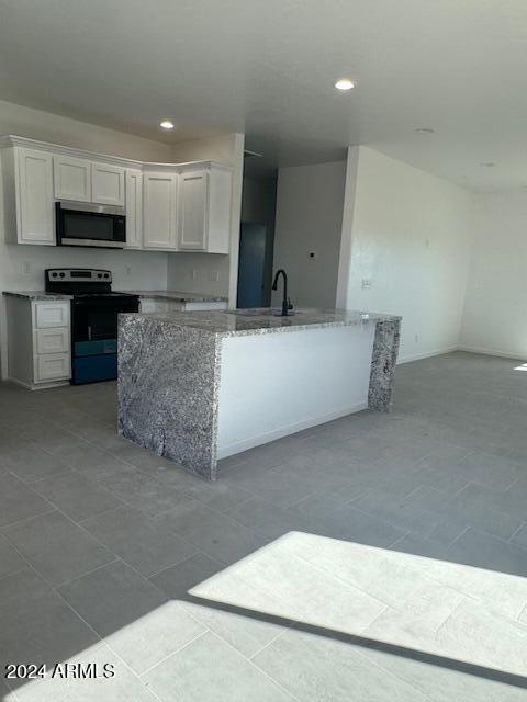 kitchen with white cabinets, light stone counters, electric stove, and sink