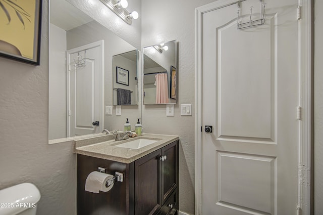 23993 N Desert Dr, Florence, AZ 85132 - bathroom featuring a textured wall, toilet, and vanity