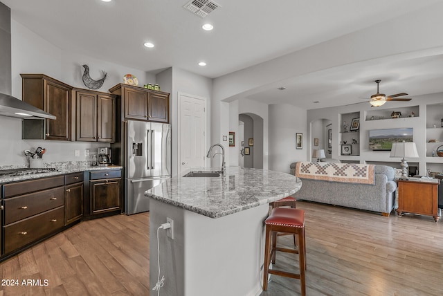 kitchen with light hardwood / wood-style flooring, stainless steel appliances, a kitchen bar, sink, and an island with sink