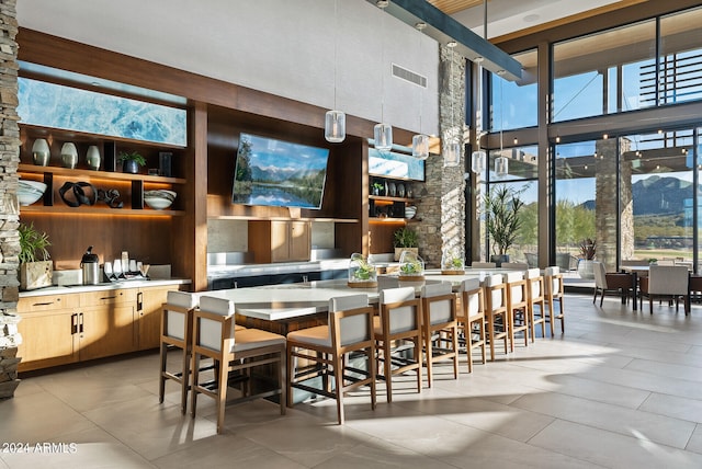 interior space with built in features, a healthy amount of sunlight, a towering ceiling, and light tile flooring