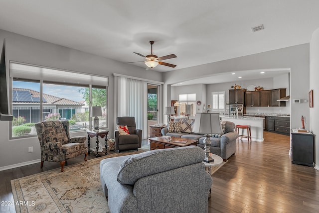 living room with a healthy amount of sunlight, ceiling fan, and dark hardwood / wood-style flooring