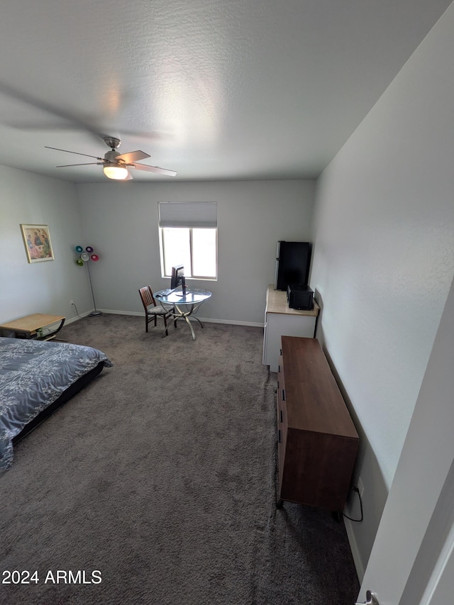 bedroom with a textured ceiling, dark carpet, and ceiling fan