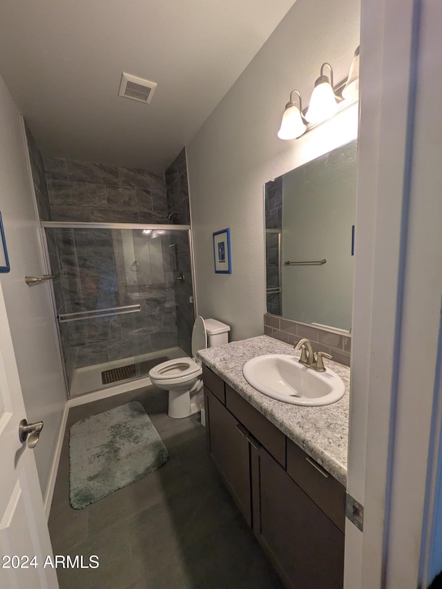 bathroom with a shower with door, vanity, and toilet