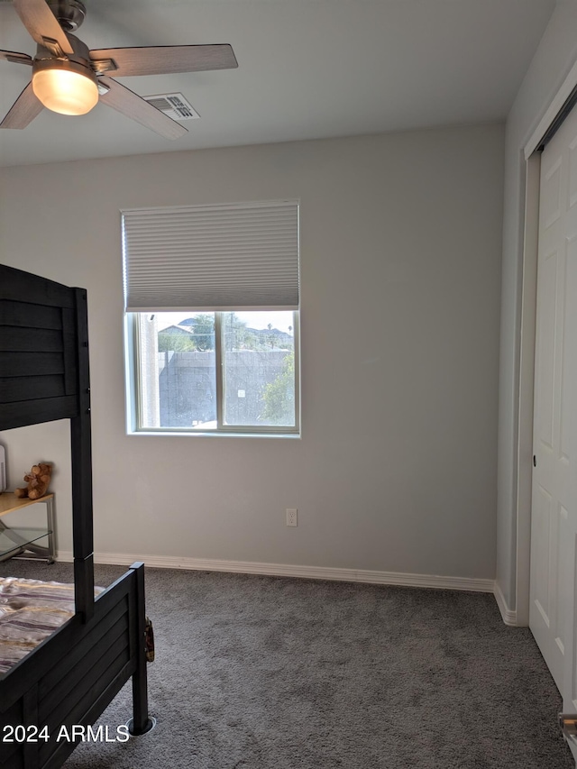 bedroom featuring ceiling fan, a closet, and dark colored carpet