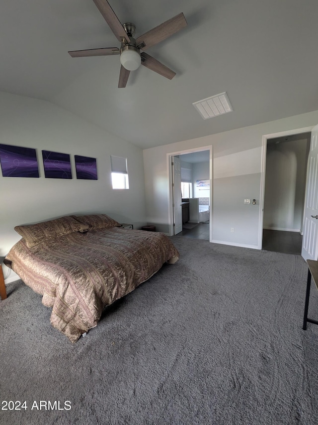 unfurnished bedroom featuring ceiling fan, dark carpet, connected bathroom, and vaulted ceiling