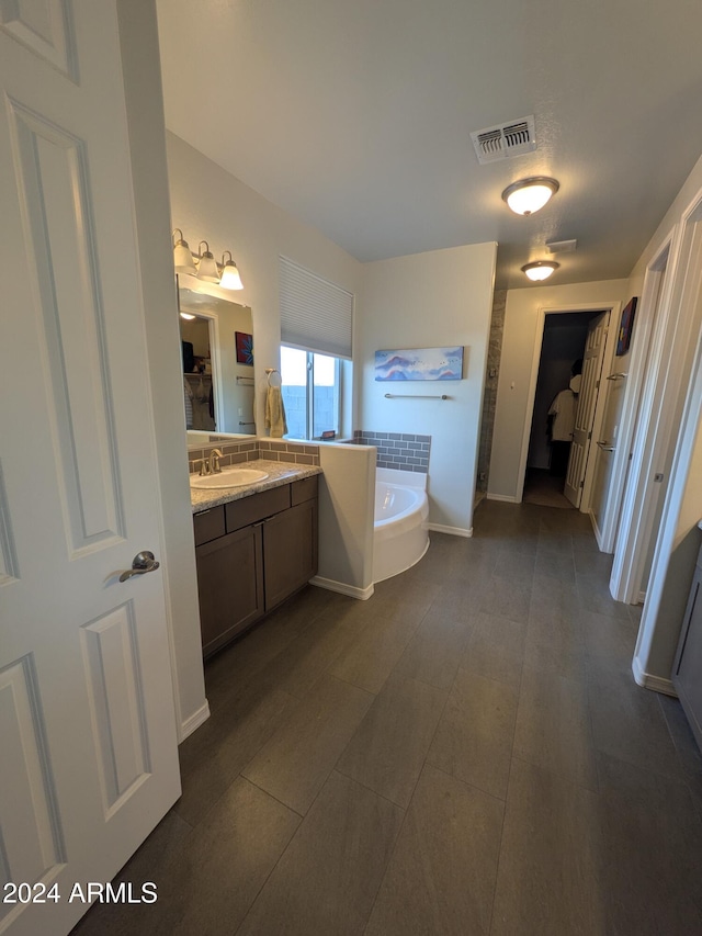 bathroom with tile patterned flooring, a bath, and vanity