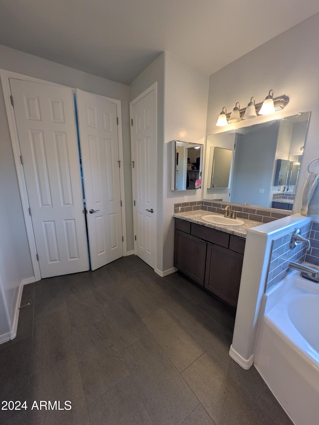 bathroom featuring a tub to relax in, tasteful backsplash, tile patterned flooring, and vanity