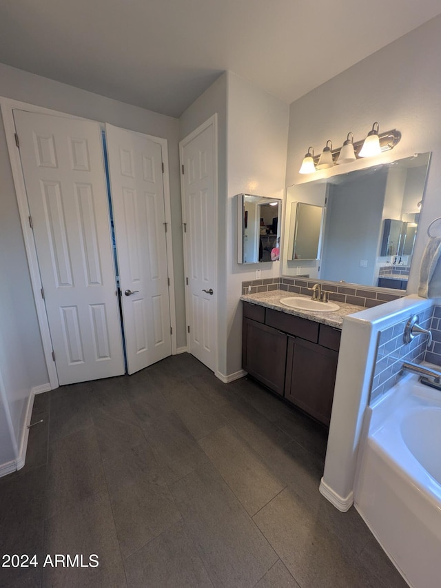 bathroom featuring tile patterned floors, a bathing tub, tasteful backsplash, and vanity