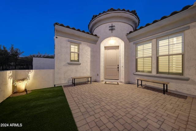 20594 W Pasadena Ave, Buckeye, AZ 85396 - exterior entry at night featuring a patio area, stucco siding, and a tiled roof
